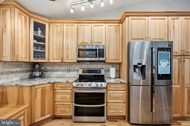 kitchen featuring tasteful backsplash, light stone countertops, light brown cabinetry, and appliances with stainless steel finishes