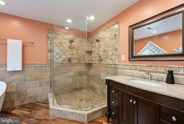 bathroom featuring hardwood / wood-style floors, vanity, walk in shower, and tile walls