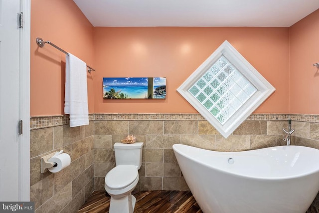 bathroom featuring hardwood / wood-style flooring, a bathtub, toilet, and tile walls