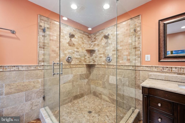 bathroom featuring an enclosed shower, vanity, and tile walls