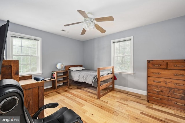 bedroom featuring ceiling fan, light hardwood / wood-style floors, and multiple windows