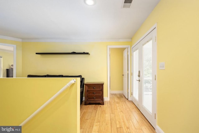 hallway with light wood-type flooring, a wealth of natural light, and french doors