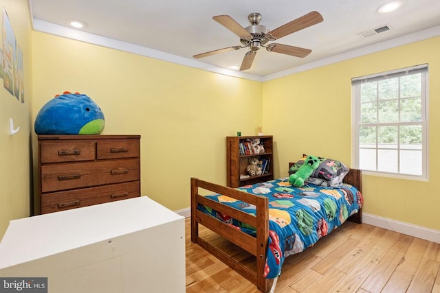 bedroom with light hardwood / wood-style floors, ceiling fan, and ornamental molding