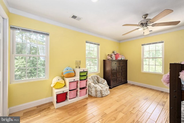 playroom featuring a healthy amount of sunlight, light wood-type flooring, and ornamental molding