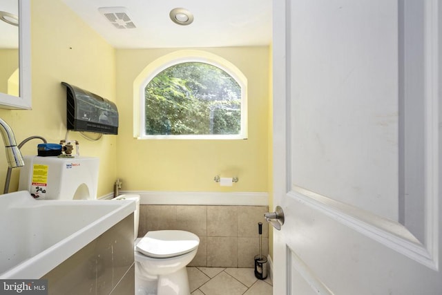 bathroom featuring tile patterned flooring, tile walls, and toilet