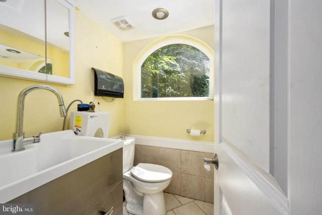 bathroom featuring tile patterned flooring, vanity, toilet, and tile walls