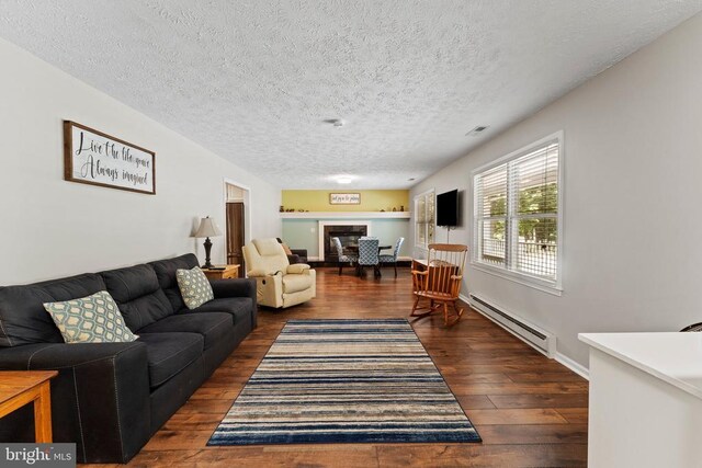 living room featuring dark wood-type flooring, baseboard heating, and a textured ceiling