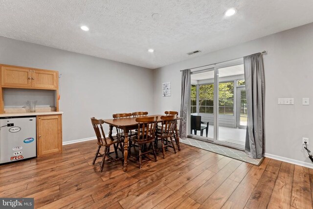 dining space featuring light hardwood / wood-style floors and a textured ceiling