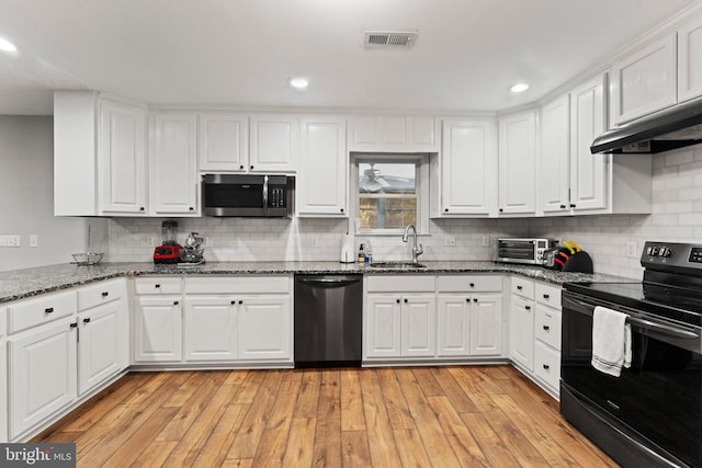 kitchen with black electric range oven, light hardwood / wood-style flooring, dishwashing machine, and white cabinetry