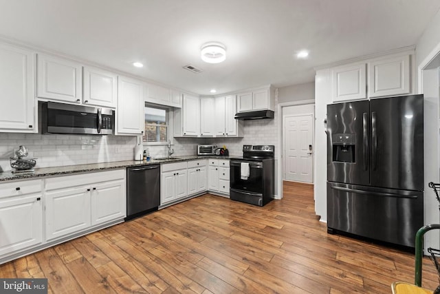 kitchen with tasteful backsplash, black appliances, hardwood / wood-style floors, white cabinets, and sink