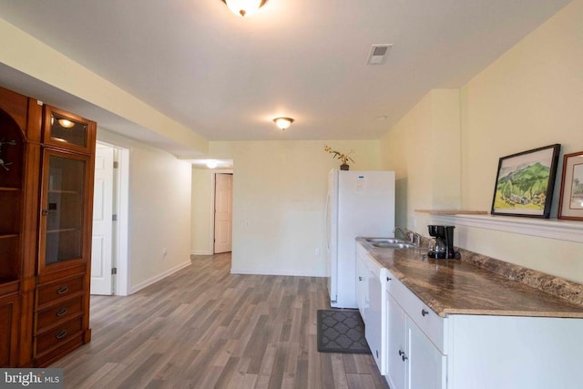 kitchen with hardwood / wood-style floors, white appliances, white cabinetry, and sink