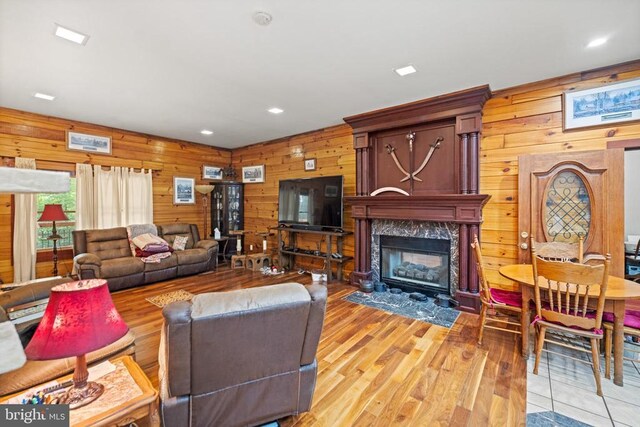 living room with a fireplace, wooden walls, and hardwood / wood-style floors