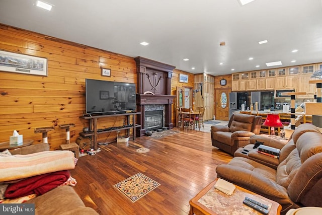 living room featuring wooden walls, wood-type flooring, and a premium fireplace