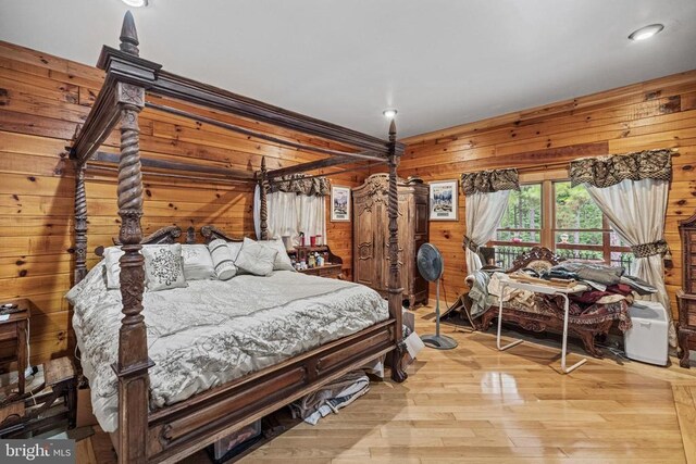 bedroom with wood walls and light hardwood / wood-style flooring