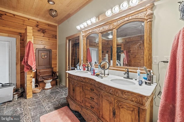 bathroom featuring wooden walls, tile patterned flooring, dual vanity, and toilet