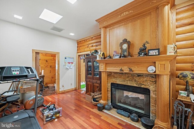 interior space featuring a skylight, hardwood / wood-style flooring, log walls, and a high end fireplace