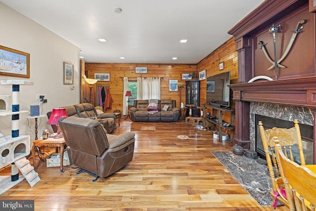 living room featuring light hardwood / wood-style flooring, a fireplace, and wooden walls