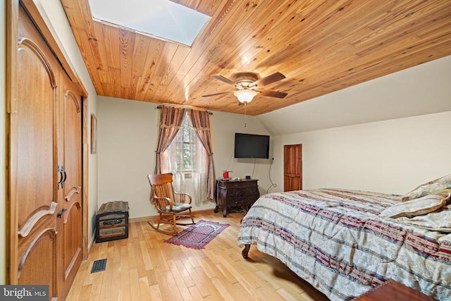 bedroom with wooden ceiling, light hardwood / wood-style floors, vaulted ceiling with skylight, and ceiling fan