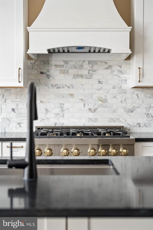 kitchen featuring white cabinets, custom range hood, tasteful backsplash, and gas range