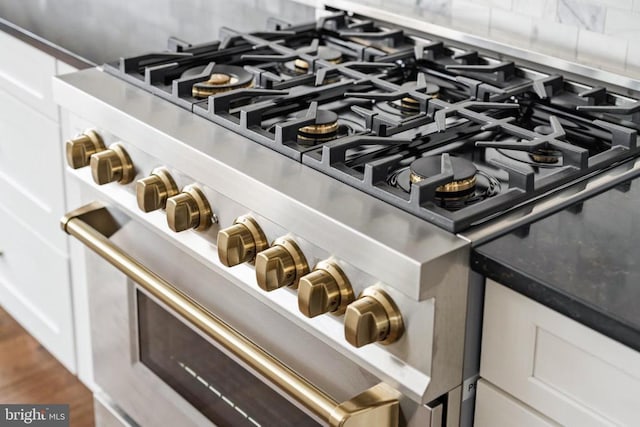 details featuring white cabinetry, range with two ovens, wood-type flooring, and decorative backsplash