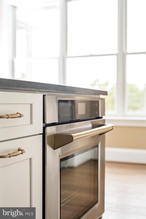 interior details featuring white cabinets, light hardwood / wood-style flooring, and stainless steel oven