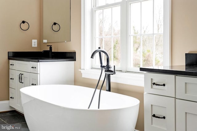 bathroom with tile patterned floors, a bathing tub, and vanity