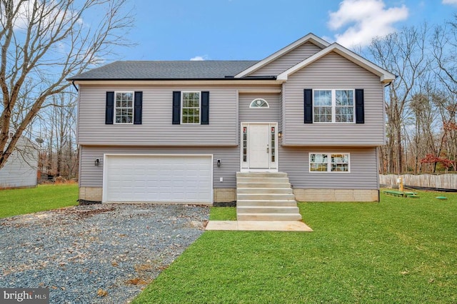 split foyer home with a garage, driveway, a front lawn, and fence