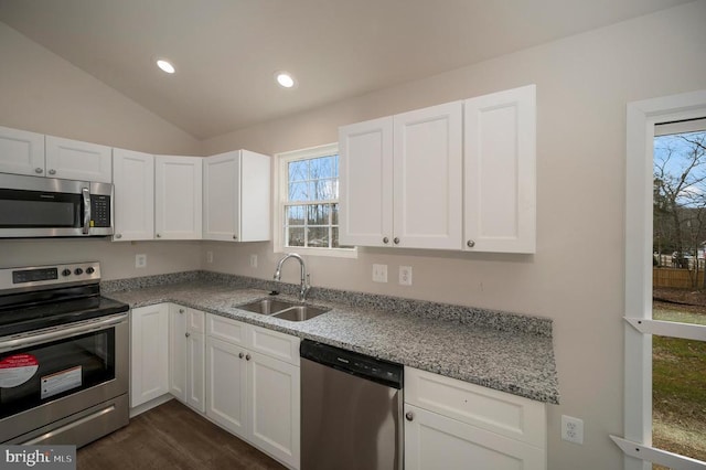 kitchen with stainless steel appliances, lofted ceiling, white cabinetry, and a sink