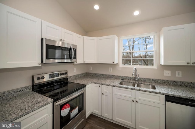 kitchen with lofted ceiling, appliances with stainless steel finishes, white cabinets, and a sink