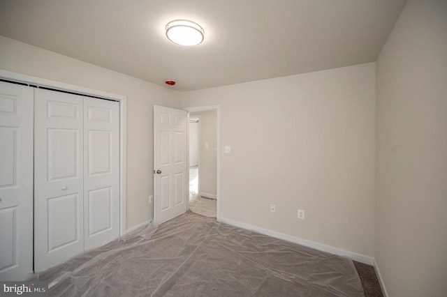 unfurnished bedroom with a closet, carpet flooring, and baseboards