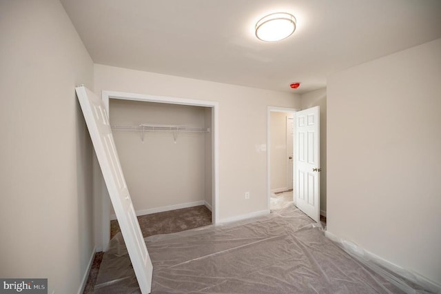 unfurnished bedroom with a closet, carpet, and baseboards