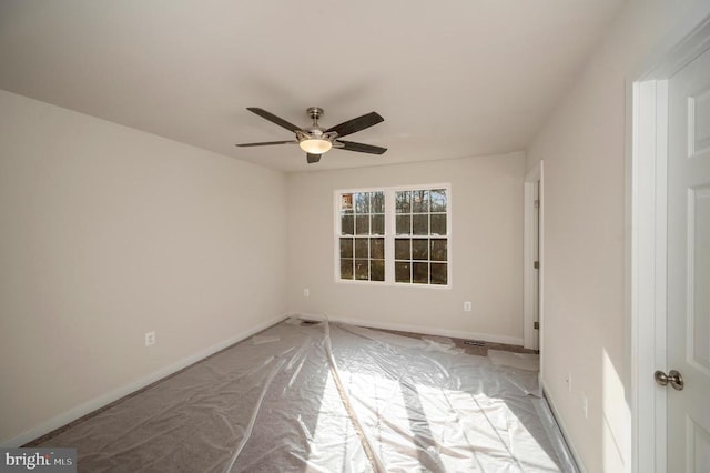 empty room with ceiling fan and baseboards