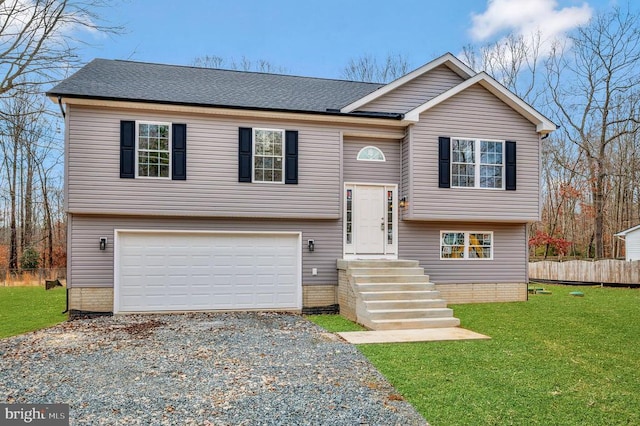 bi-level home with an attached garage, fence, roof with shingles, a front lawn, and gravel driveway