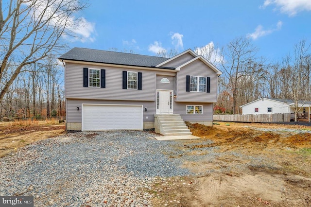 bi-level home with driveway, a garage, and fence