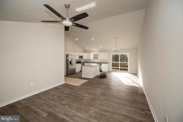 unfurnished living room featuring baseboards, high vaulted ceiling, dark wood-type flooring, and ceiling fan with notable chandelier