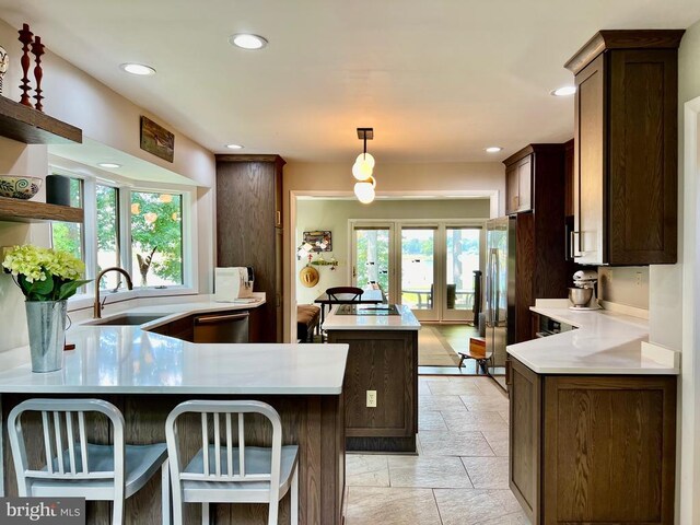 kitchen with a kitchen bar, dishwasher, light tile patterned floors, sink, and kitchen peninsula