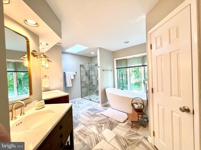 bathroom featuring tile patterned flooring, separate shower and tub, a skylight, and vanity