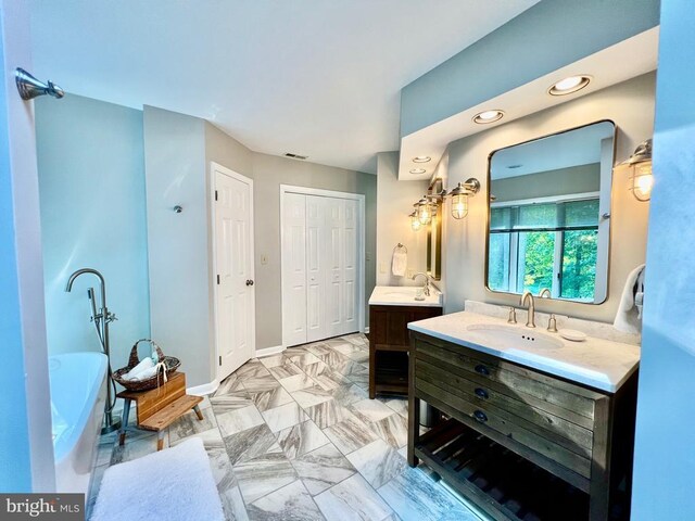 bathroom with a washtub, vanity, and tile patterned floors