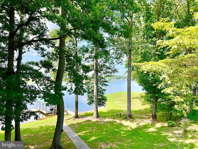 surrounding community featuring a dock, a yard, and a water view