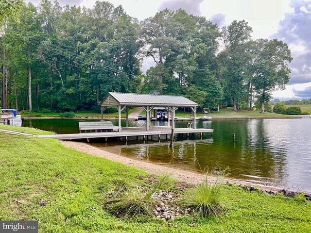 view of dock with a lawn and a water view