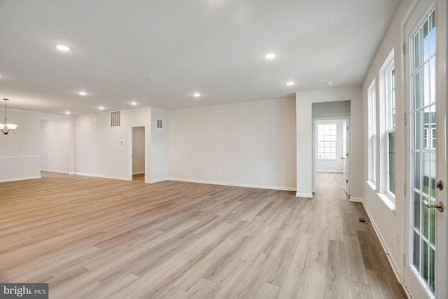 spare room featuring light hardwood / wood-style floors and a chandelier