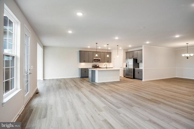 kitchen featuring decorative light fixtures, gray cabinetry, stainless steel appliances, and light hardwood / wood-style floors