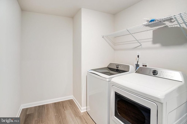 clothes washing area featuring light hardwood / wood-style flooring and separate washer and dryer