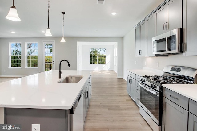 kitchen with a center island with sink, sink, appliances with stainless steel finishes, and a healthy amount of sunlight