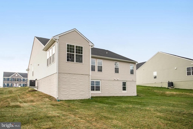 rear view of house with central AC and a yard