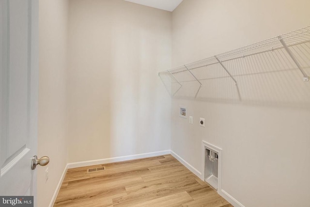 clothes washing area with hookup for an electric dryer, hookup for a washing machine, and hardwood / wood-style flooring