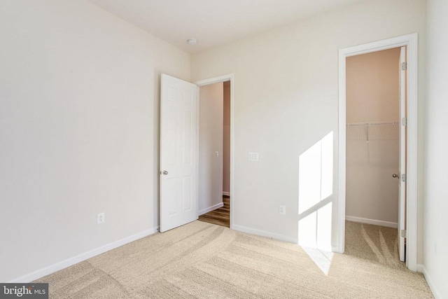 unfurnished bedroom featuring a spacious closet, light carpet, and a closet