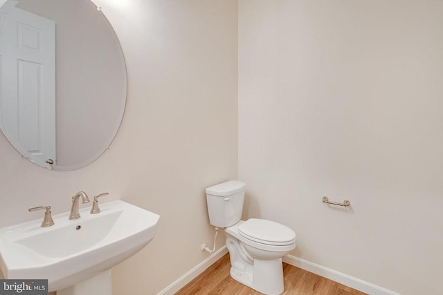 bathroom with toilet, wood-type flooring, and sink