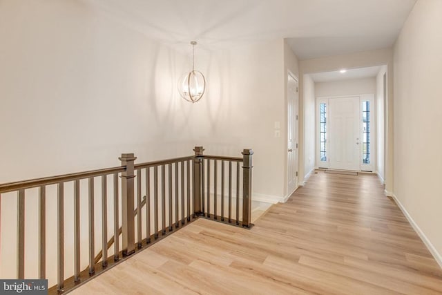 hall with wood-type flooring and an inviting chandelier