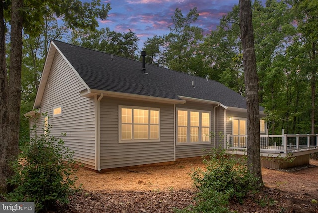 back house at dusk with a wooden deck